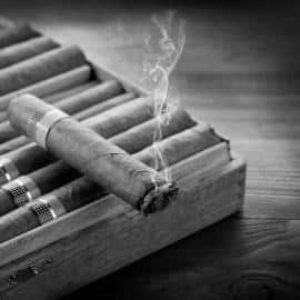 Smoking cuban cigar over box  on wood background
